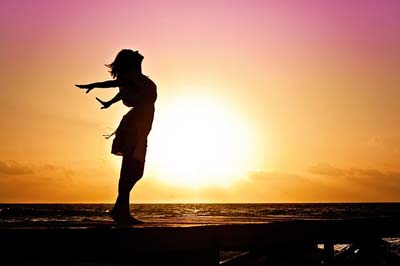 A sunset silhouette of a carefree woman