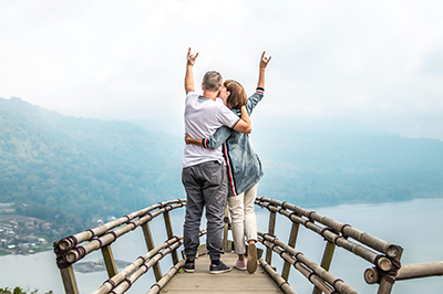 A photo of a man and woman standing at a high point with arms linked and raised