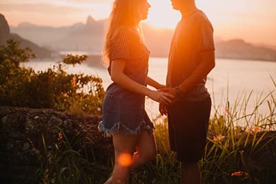 A photo of a man and woman holding hands, with the sunset in the background