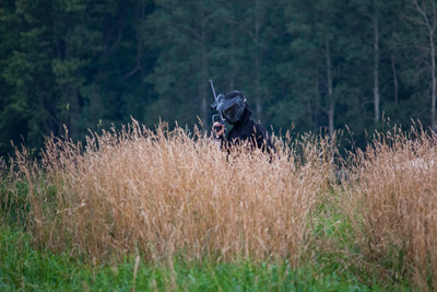 A photo of a person standing in a paintball field.