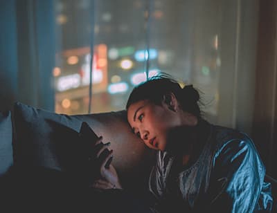 A photo of a woman solemnly looking at her phone